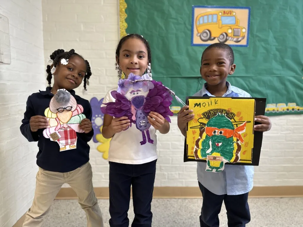 Students holding their turkeys in disguise projects.