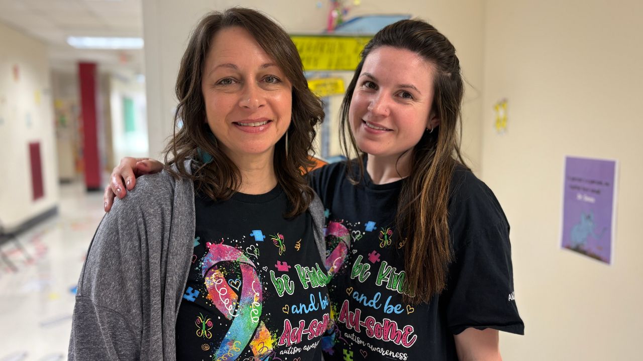 2 people smiling wearing autism awareness shirts