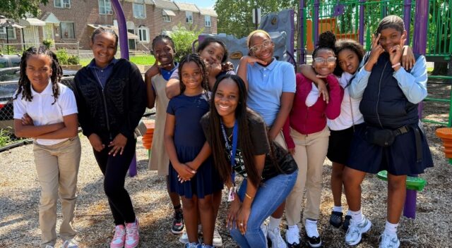 Smiling students and an adult on a playground.